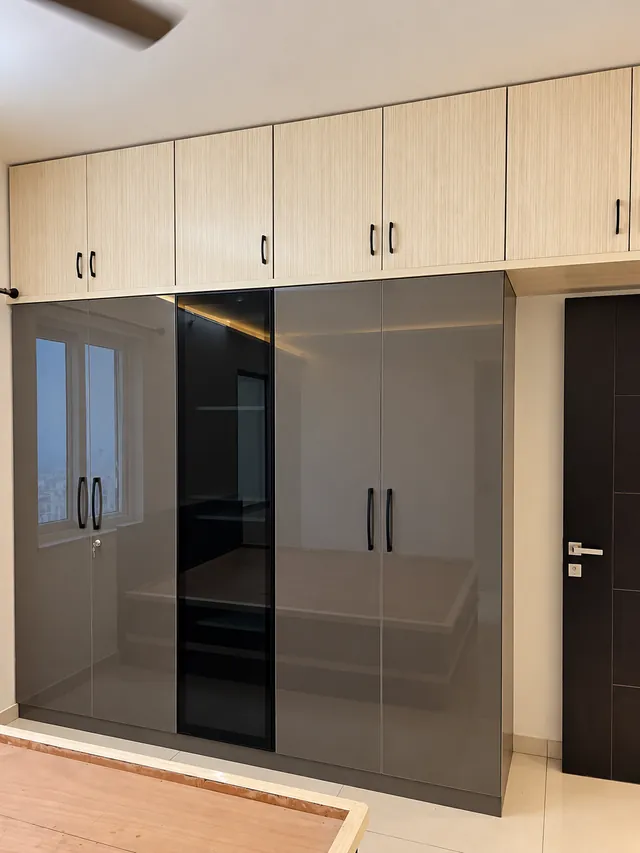 Glossy grey wardrobe with black glass shutter, completed by Casa Interiors in Hyderabad